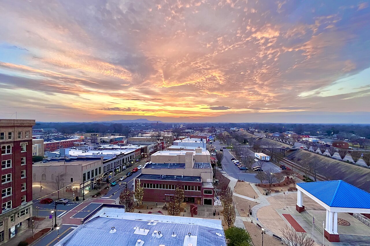 Aerial view of downtown Gastonia, North Carolina, with historic rooftops and rolling hills at sunset